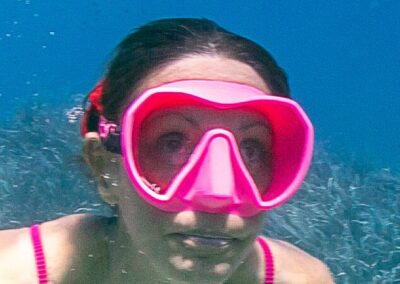 Femme souriante en masque de plongée rose fluo sous l'eau, symbole de bien-être aquatique et relaxation marine