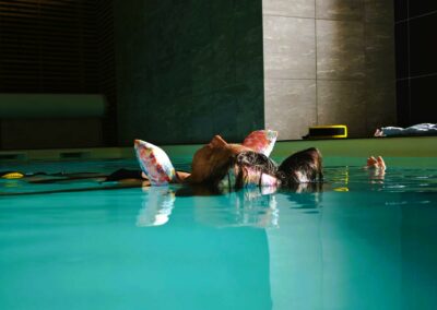 Femme en relaxation aquatique à Bastia dans piscine chauffée, bras flottants avec accessoires colorés