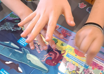 photo de mains d'enfants qui jouent a un jeu sur les animaux marins